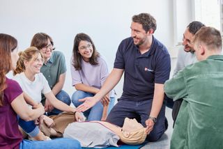 Erste-Hilfe-Ausbilder der Malteser steht vor einer Gruppe in einem Erste-Hilfe-Kurs
